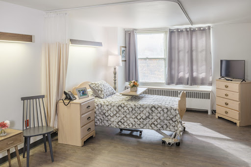 A comfortable and well-lit hospital room featuring a patient bed, bedside table, and a cozy atmosphere.