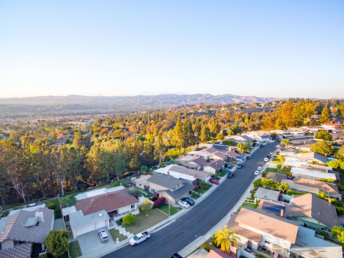 Aerial view of a suburban neighborhood with houses and trees at sunset.