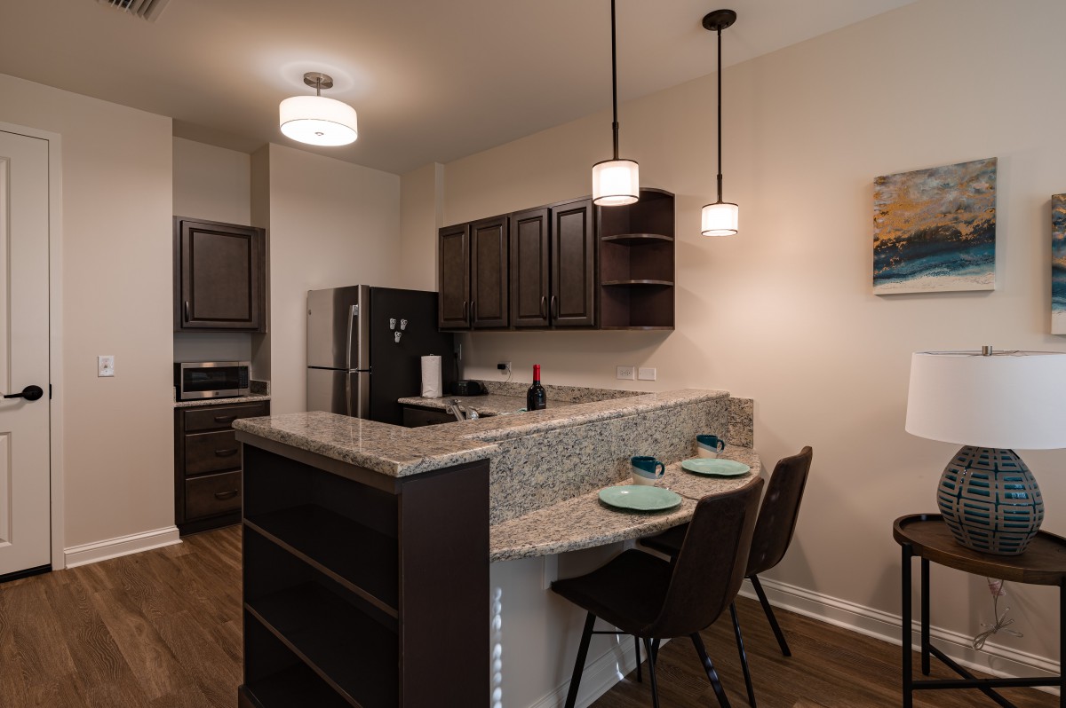 A modern kitchen with a breakfast bar, featuring pendant lighting and bar stools.