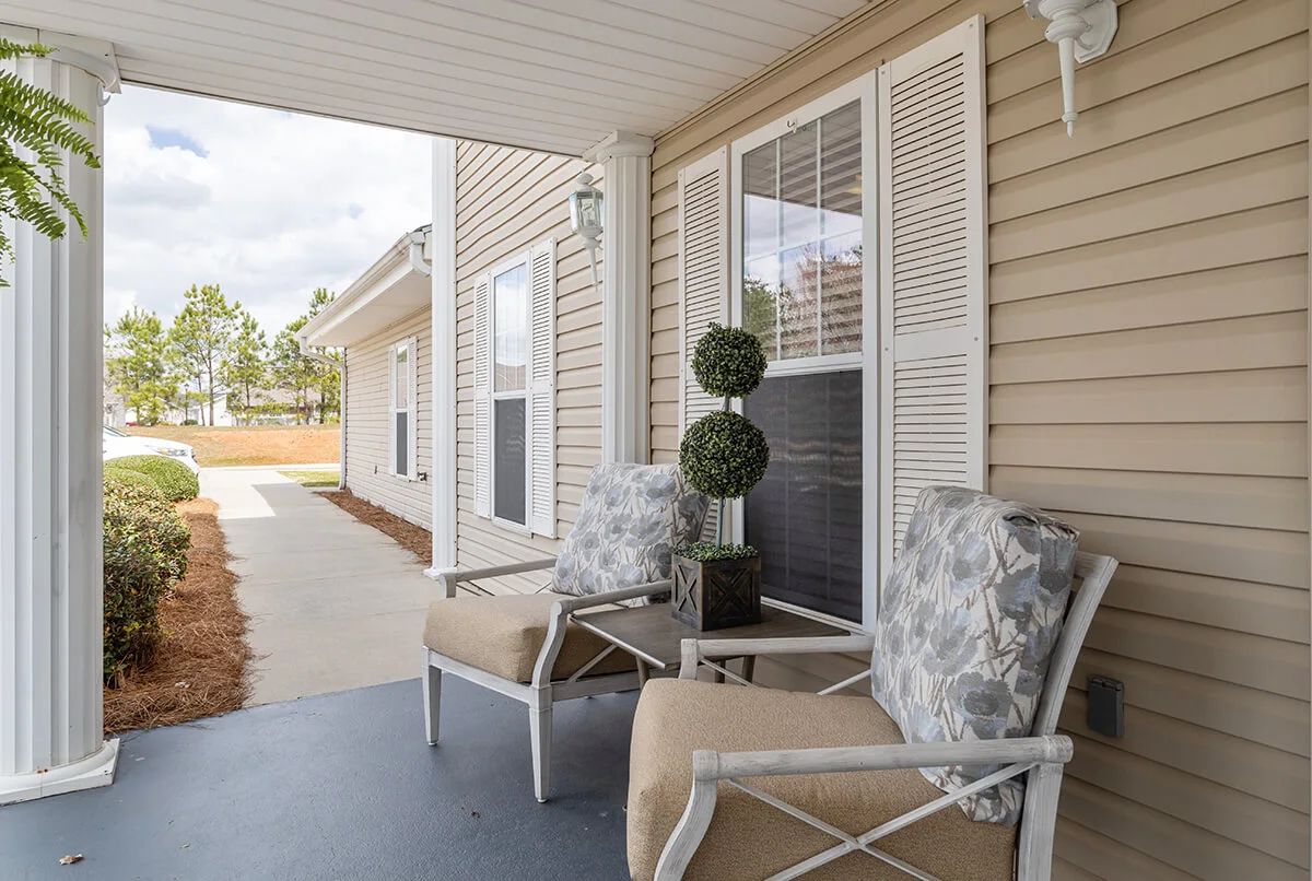 A cozy outdoor porch area with comfortable chairs and decorative plants.