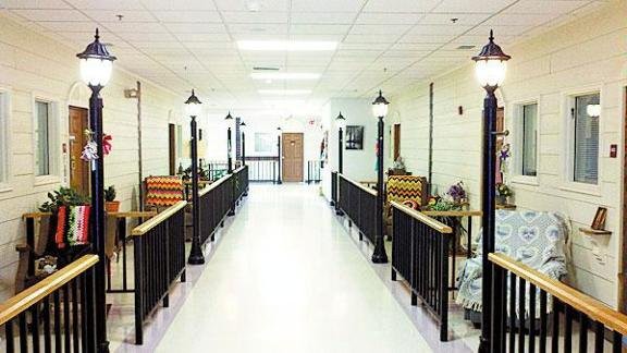 A bright, well-lit hallway with decorative lamps and railings, featuring furniture on both sides.