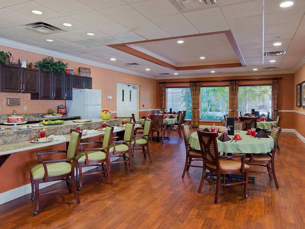 A spacious dining room with neatly arranged tables and chairs, featuring large windows and wooden flooring.