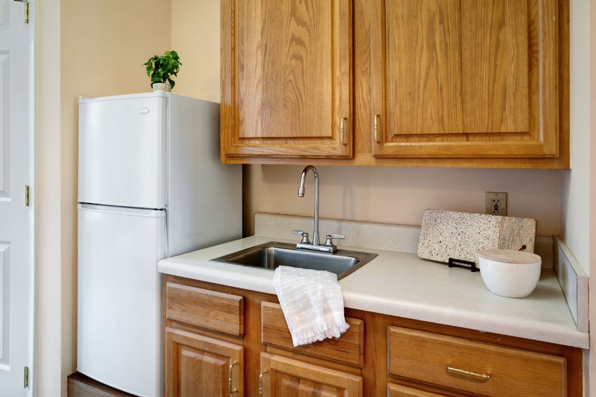 A cozy kitchen corner with wooden cabinets, a fridge, and a sink.