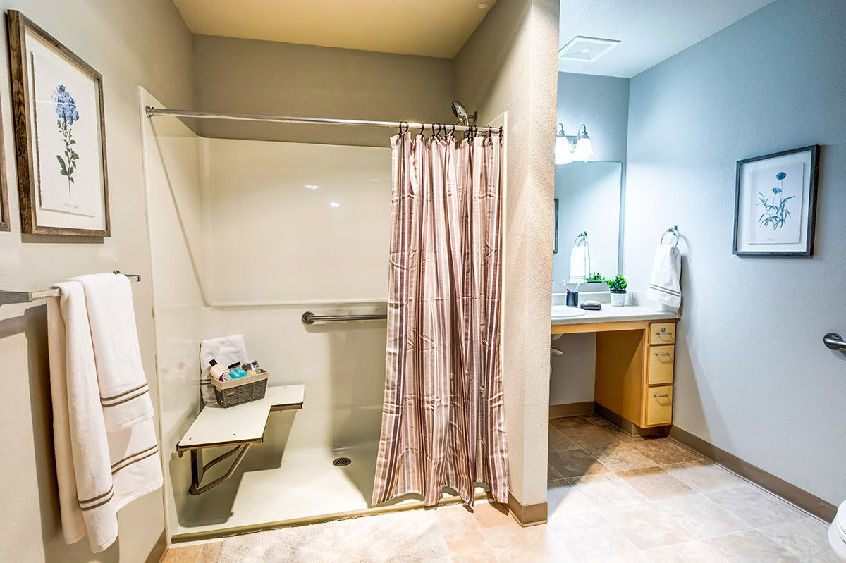 A well-organized bathroom featuring a shower with a curtain and a vanity with a sink and mirror.