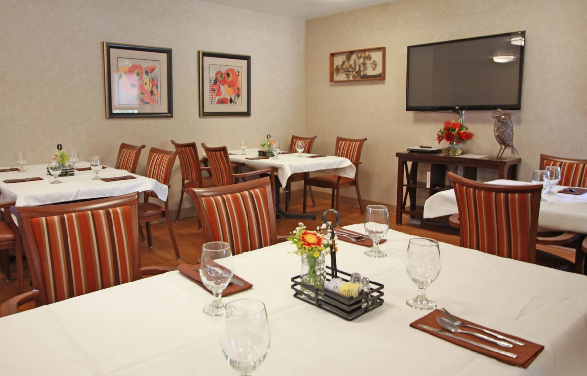 An elegantly decorated dining room with neatly arranged tables and chairs, featuring artwork on the walls.