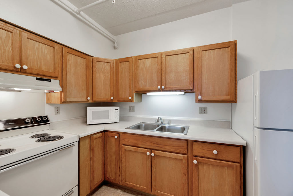 A kitchen with wooden cabinets, a microwave, and a double sink.