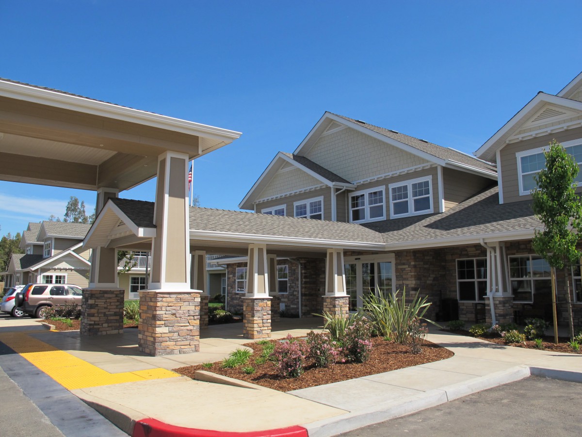 A modern residential building with well-maintained landscaping and a clear blue sky.