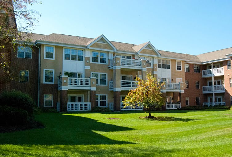 A residential apartment building with well-maintained lawns and balconies on a sunny day.