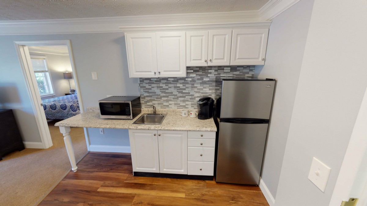 A modern kitchenette with a microwave, refrigerator, and coffee maker.