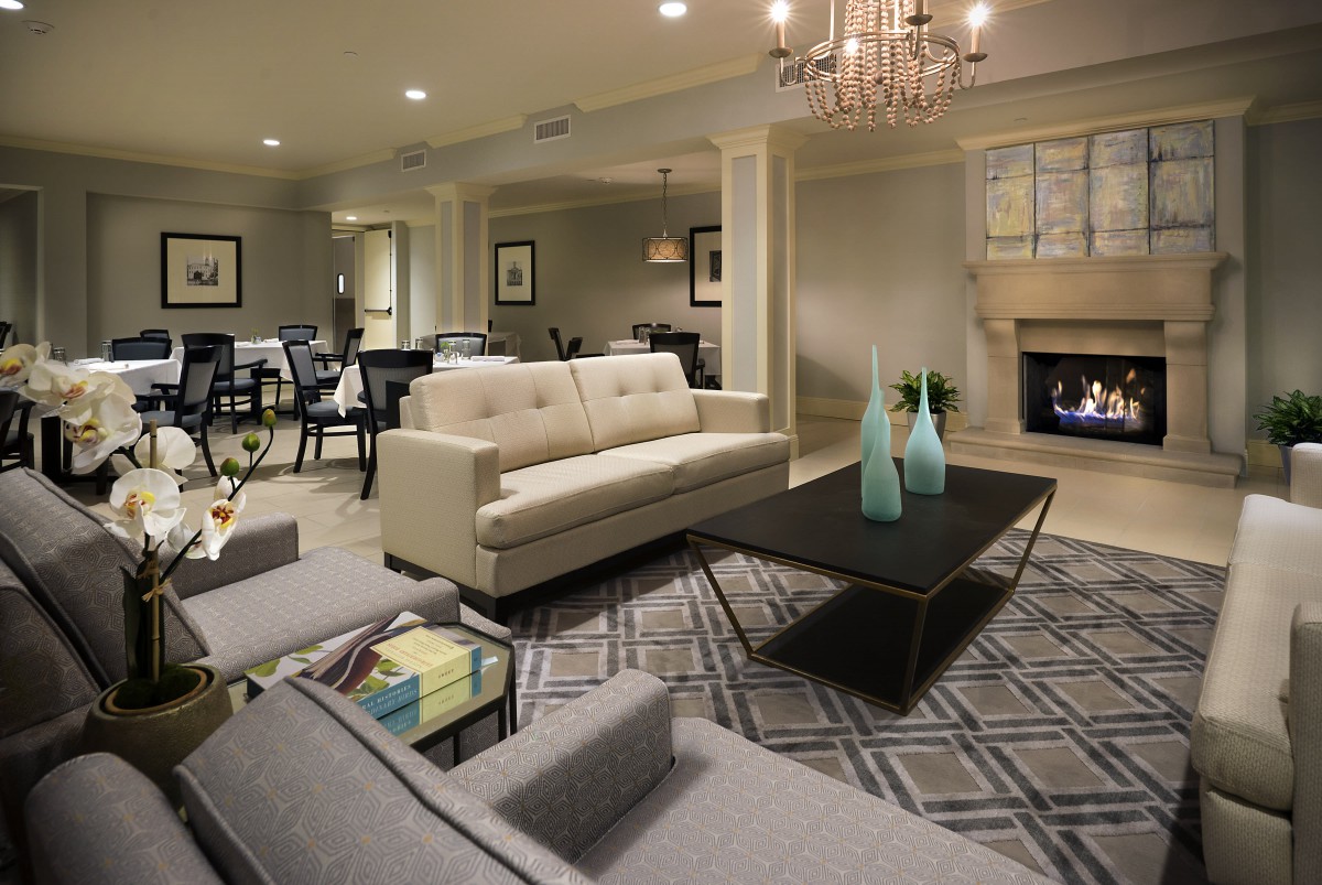 A modern living room with a neutral color scheme, featuring a sofa, coffee table, and fireplace.