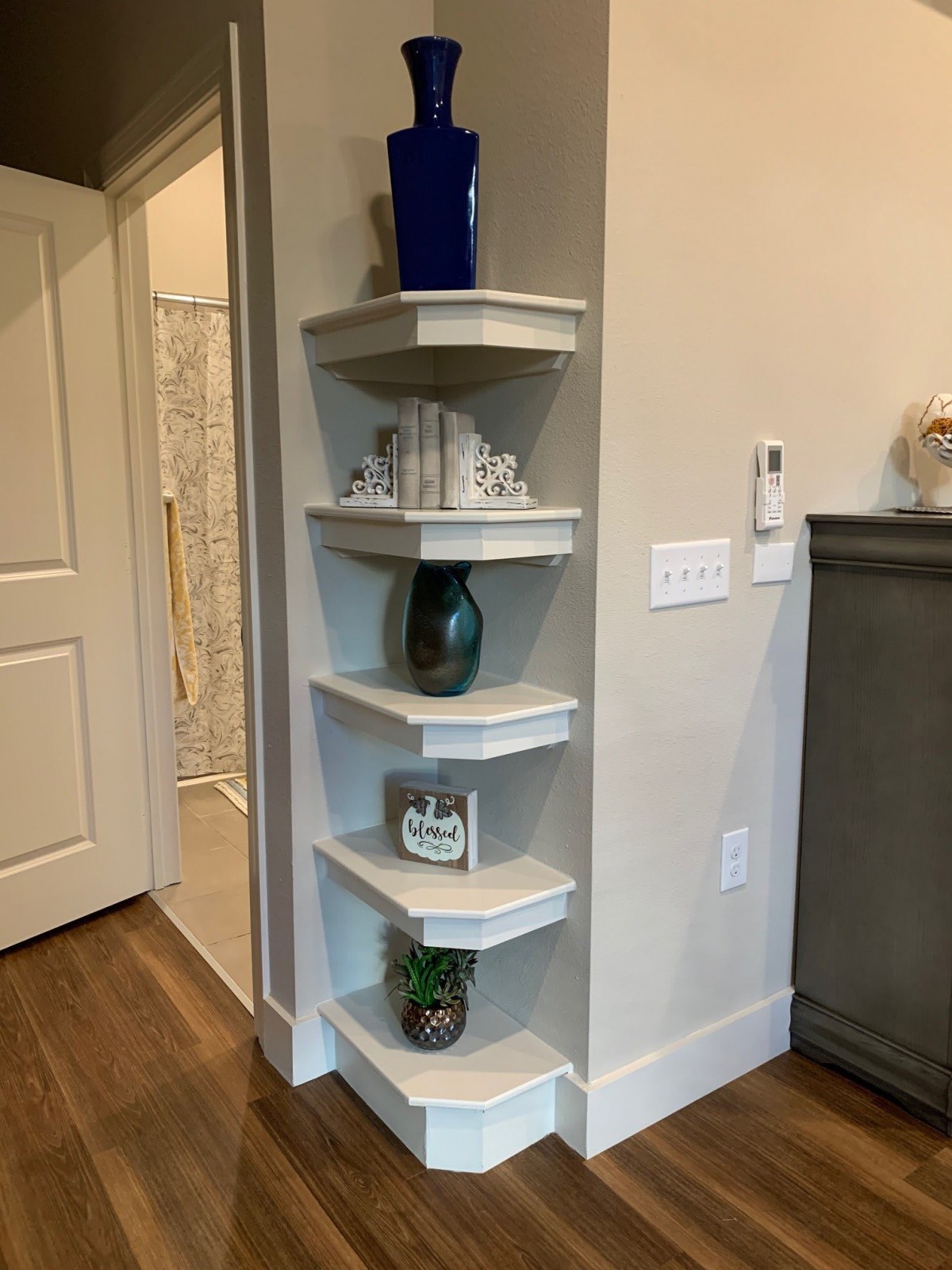 A neatly arranged corner shelf with various decorative items in a home's interior.