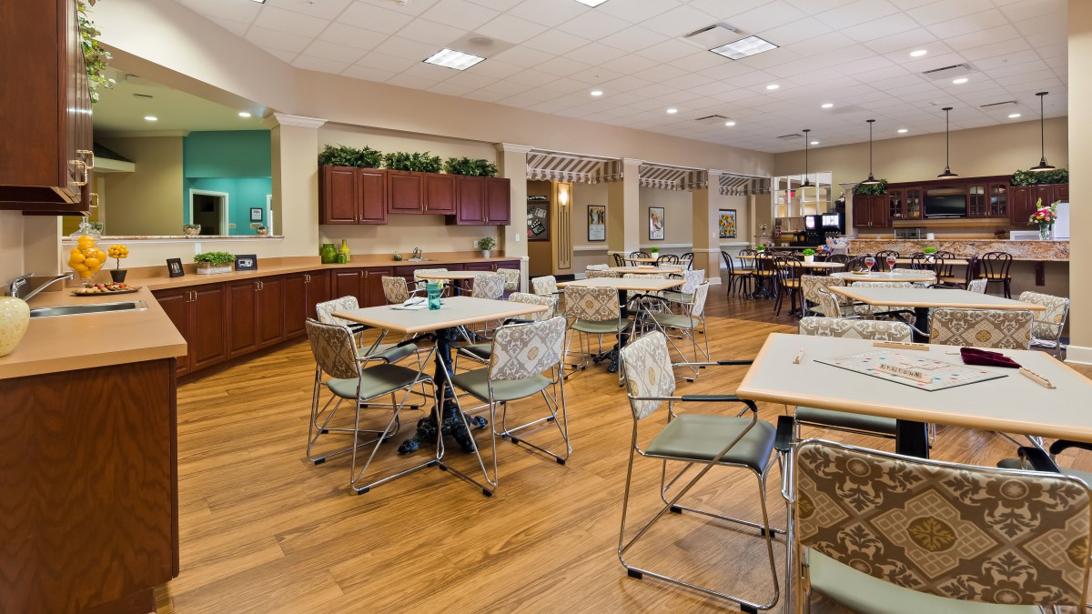 A modern dining area with wooden floors, tables, and chairs arranged neatly.