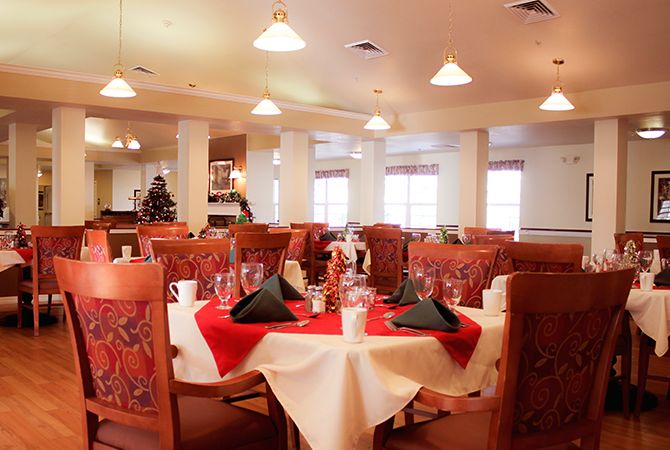 An elegantly set dining area in a restaurant, featuring round tables with red and white tablecloths and neatly arranged chairs.