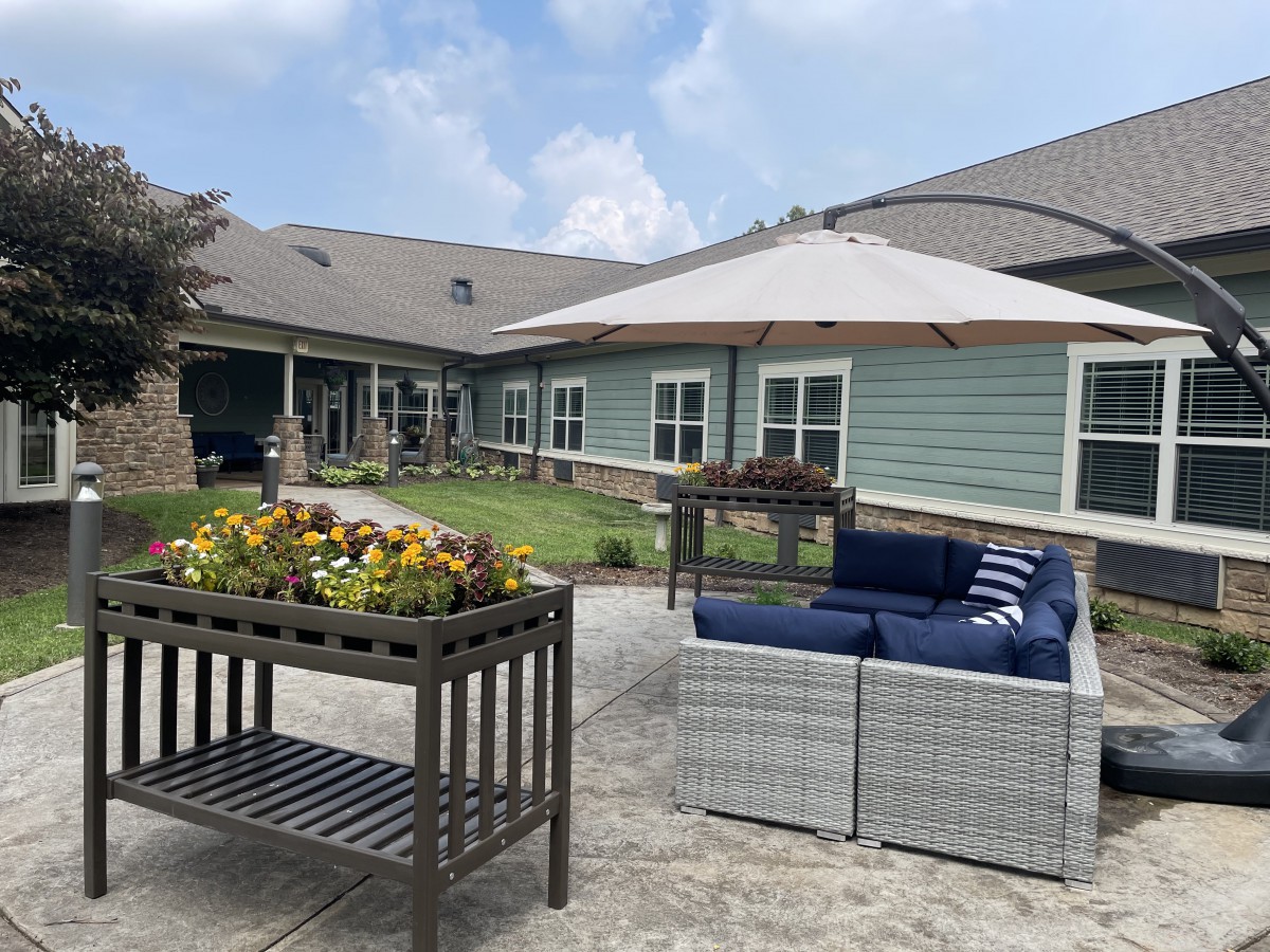 A peaceful outdoor patio area with comfortable seating, a garden planter, and a large umbrella.