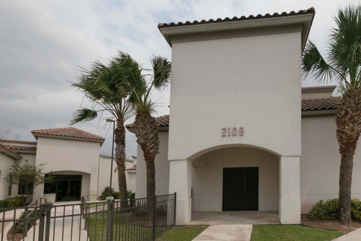 A suburban house with palm trees in the front yard.