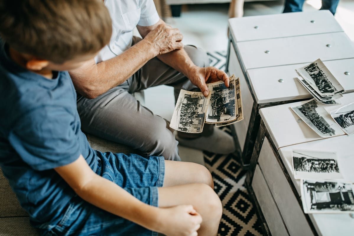 A child and an adult looking through a photo album together, cherishing memories.
