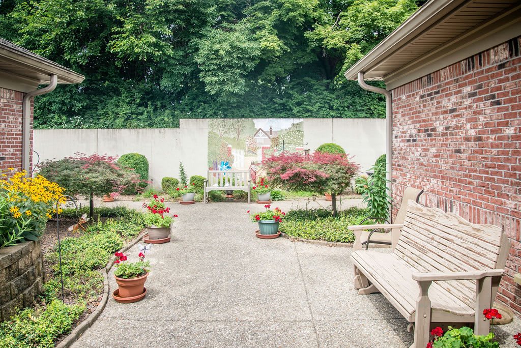 A tranquil garden patio with potted plants and a wooden bench.