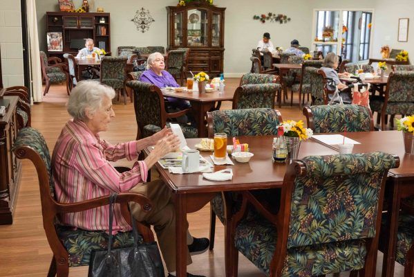 Elderly residents enjoying a meal in a senior living community dining hall.