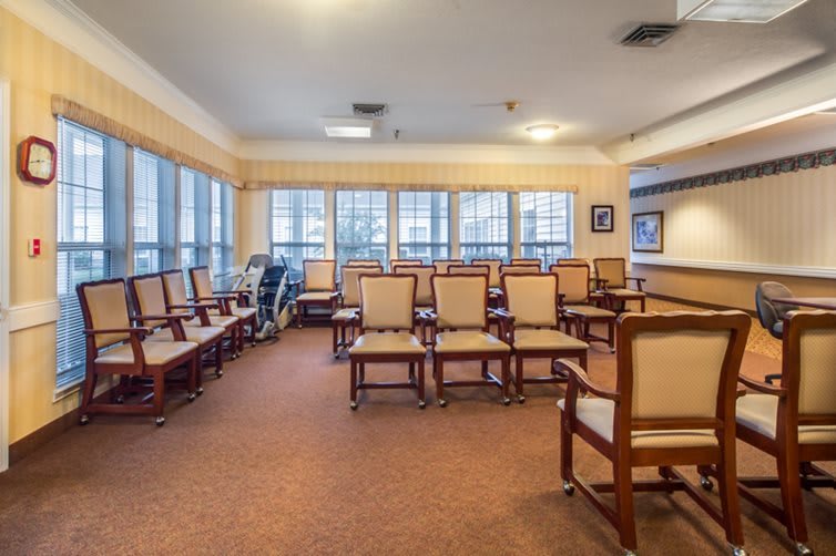 An empty waiting area with rows of chairs and bright natural light from large windows.