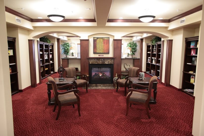A cozy library with seating area, fireplace, and bookshelves.