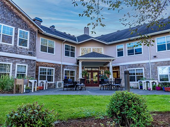 A two-story residential building with a well-maintained lawn and outdoor seating area.