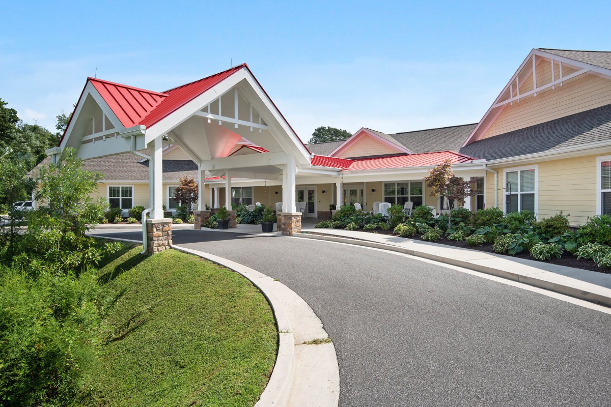 A modern building with a red roof and a circular driveway leading to the main entrance.