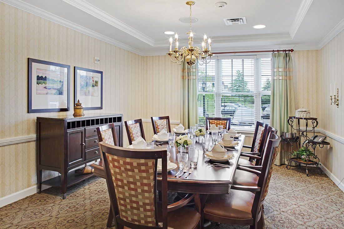 A formal dining room with a long table, elegant chairs, and a chandelier.