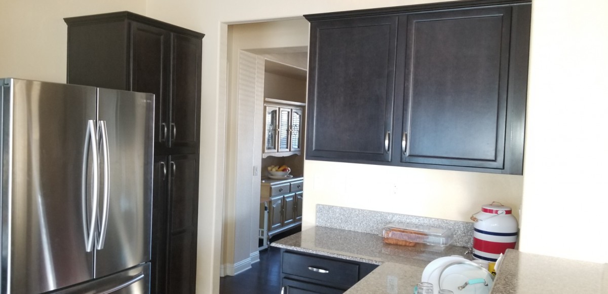 A modern kitchen with dark wood cabinets and a glimpse into an adjoining room.