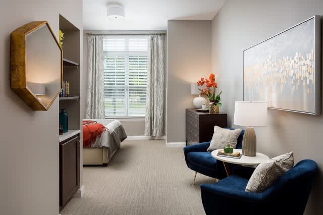 A modern bedroom with stylish furniture and ample natural light from a large window.