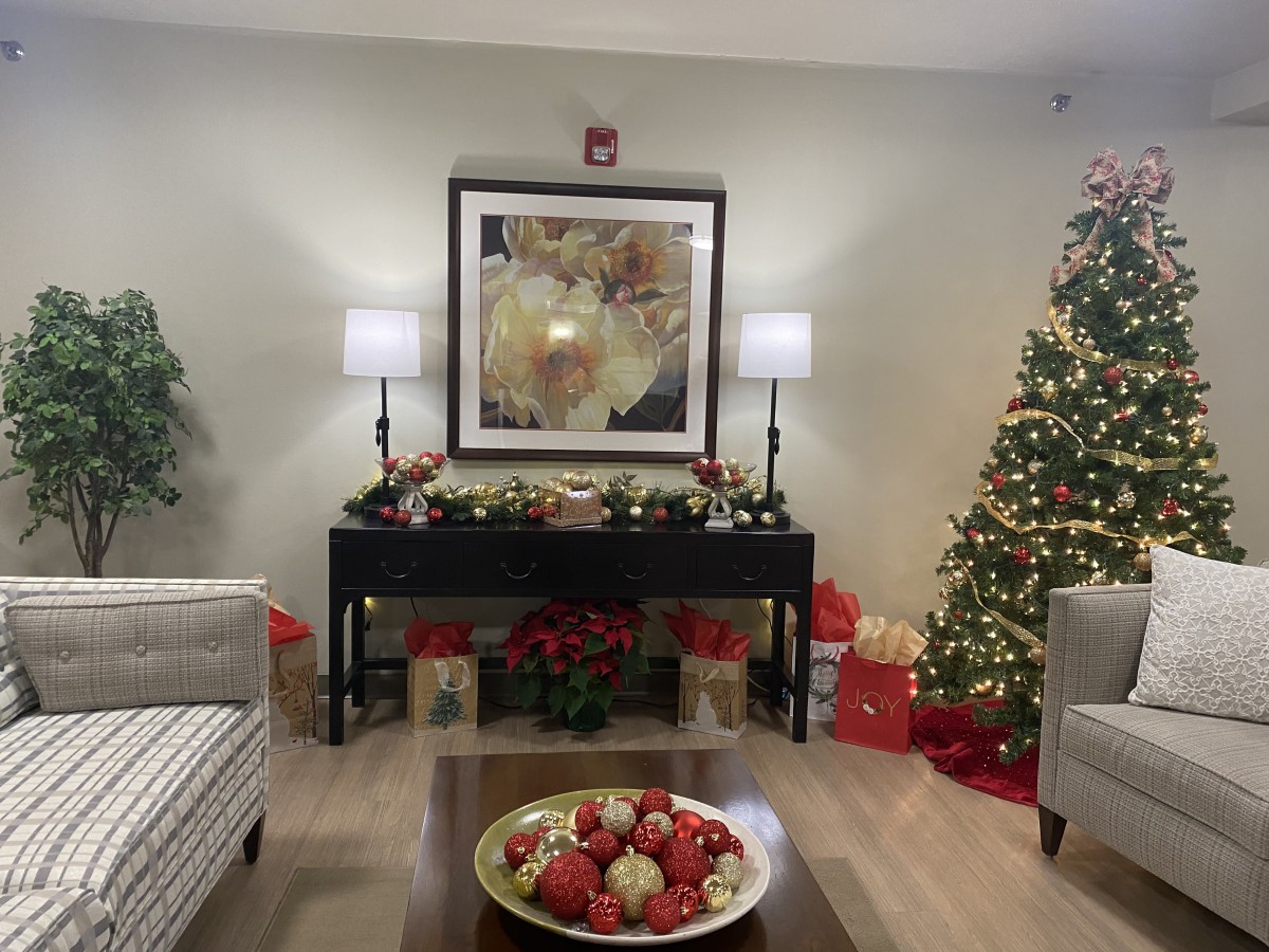 A cozy living room decorated with a Christmas tree, gifts, and festive holiday decorations.
