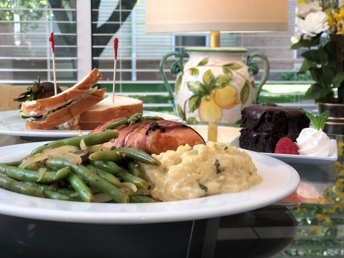 A delicious meal featuring salmon, green beans, mashed potatoes, a sandwich, and chocolate cake with raspberries.