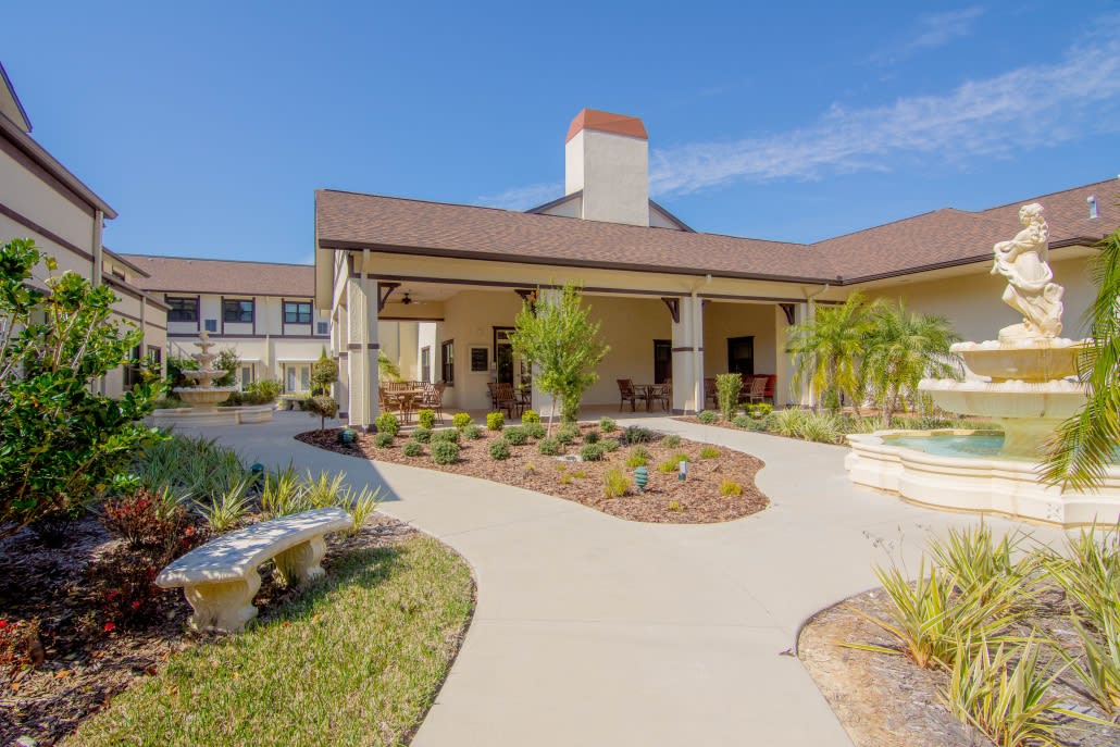 A modern building with a landscaped garden and pathway under a clear blue sky.