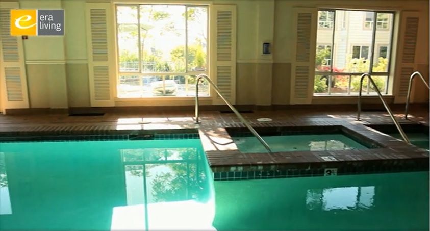 An indoor swimming pool with sunlight streaming through large windows.