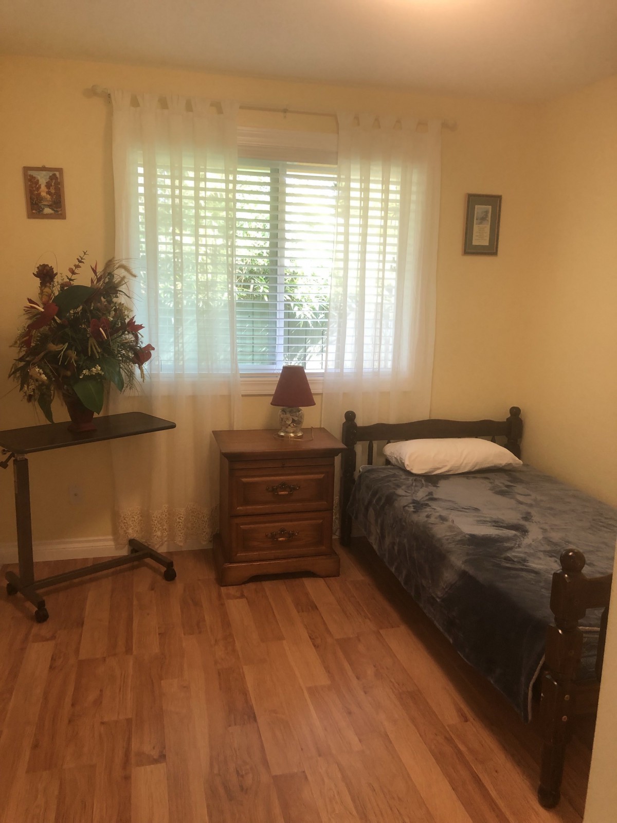 A small, cozy bedroom with a single bed and a window letting in natural light.