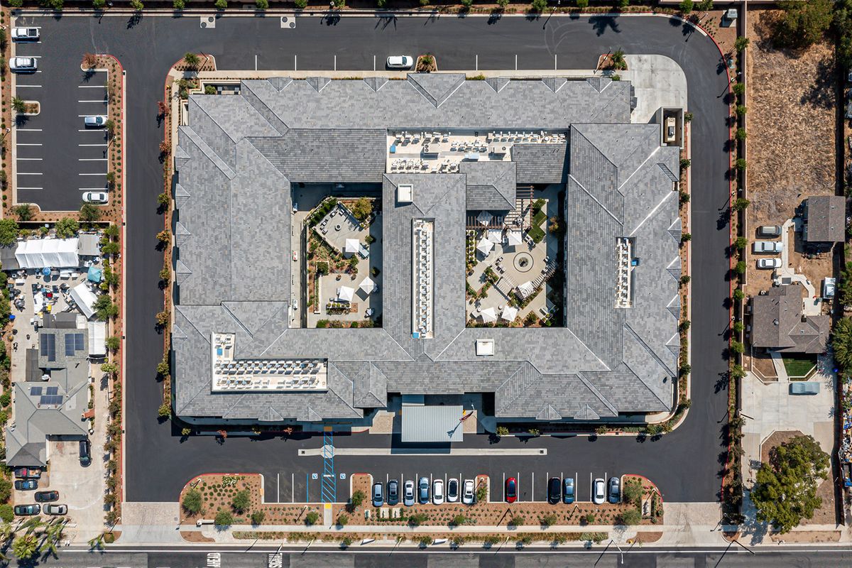 Aerial view of a large commercial building with a central courtyard and adjacent parking lot.