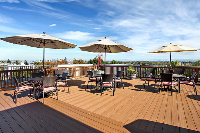 A spacious outdoor patio with tables and umbrellas, offering a scenic view under a clear blue sky.