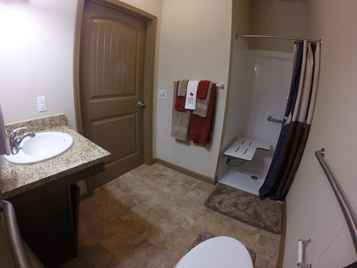 A modern bathroom with a shower, sink, and neatly hung towels.