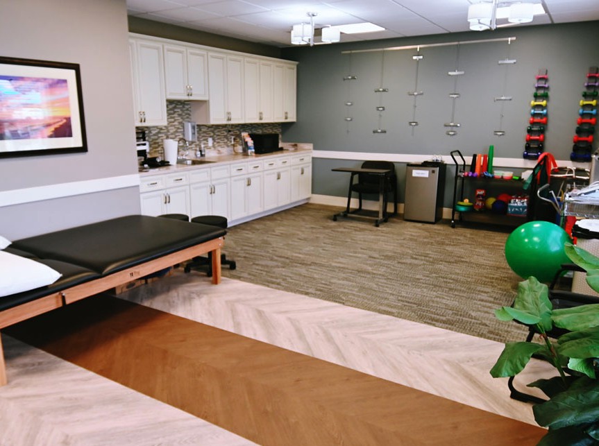 A well-equipped physical therapy clinic with various exercise tools and a treatment table.