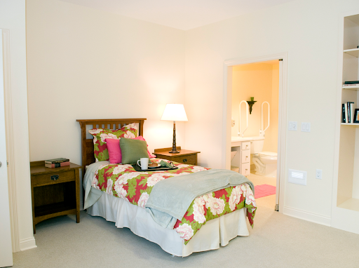 A cozy bedroom featuring floral bedding, a bedside lamp, and an inviting bathroom entrance.
