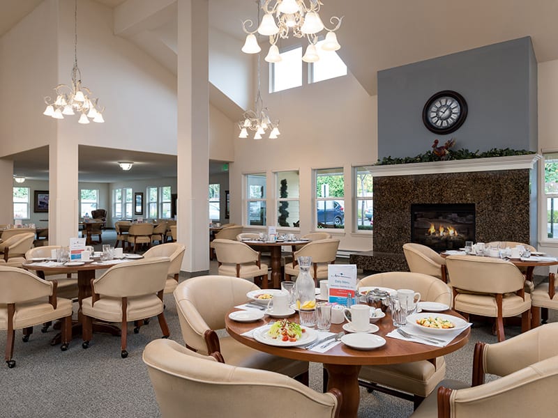 A cozy dining room interior with elegant table settings and a warm fireplace.