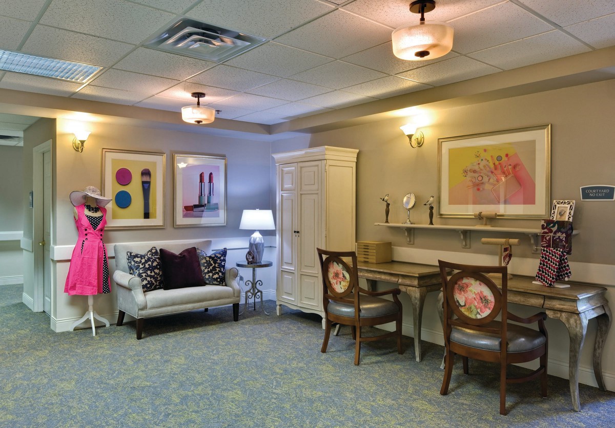 A stylishly decorated room featuring a desk, chairs, sofa, and colorful artwork.