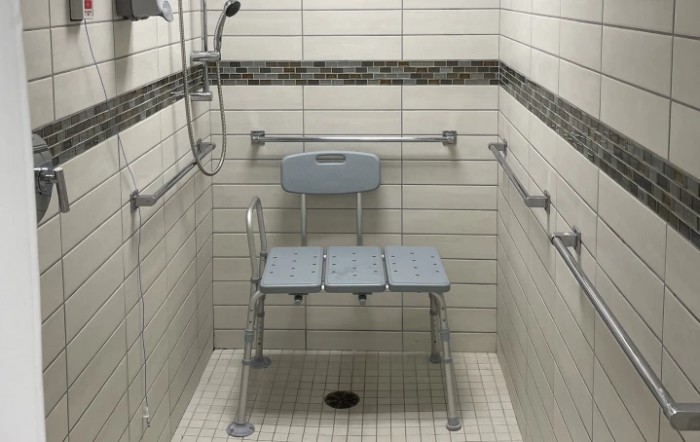 An accessible shower setup with a shower chair and grab bars for safety.