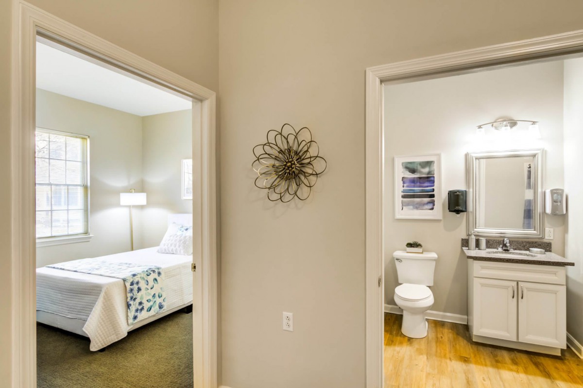 A view of a hallway leading to a bedroom on the left and a bathroom on the right, showcasing a modern interior design.
