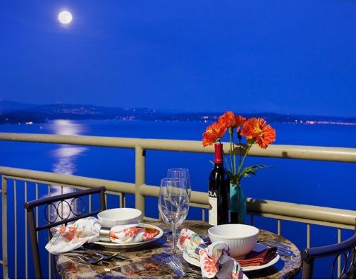 A romantic dinner setup on a balcony overlooking the moonlit water.