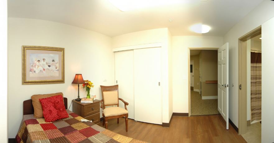 A cozy bedroom with a chair, lamp, and closet.