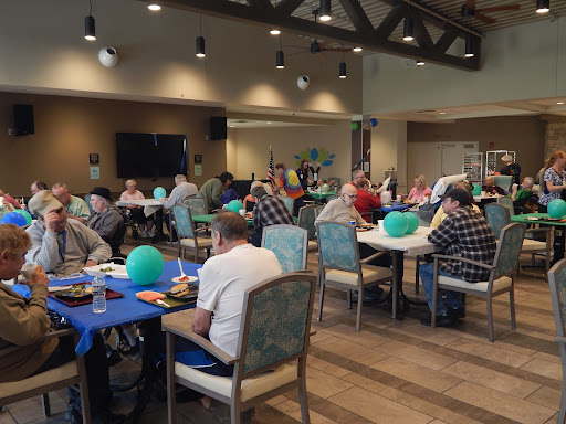 A lively community gathering featuring people enjoying food and conversation around tables.