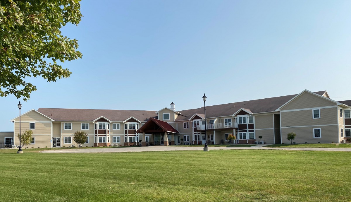 A large residential building with a well-maintained lawn and a covered entrance.