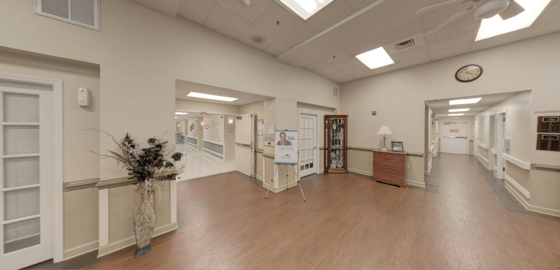 A hallway in a medical facility with a reception area and directional signage.