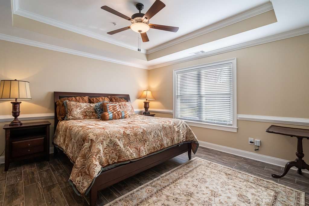 A cozy bedroom with a large bed, ceiling fan, and natural lighting through the window.