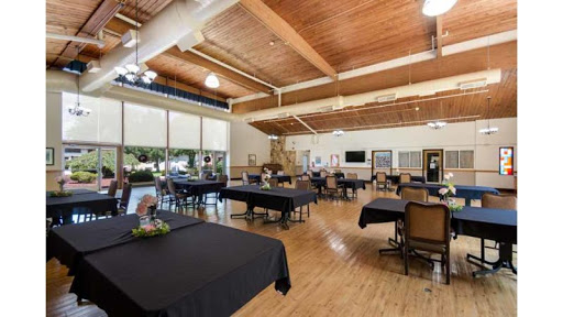 A spacious indoor dining area with black tablecloths and a wooden ceiling, ideal for gatherings and events.